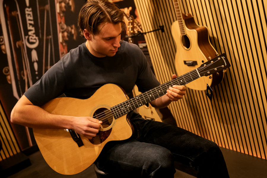 Klant speelt een akoestische gitaar in de gitaarafdeling